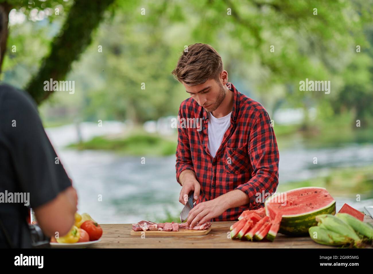 Man cooking tasty food on barbecue grill for outdoor french dinner party  near the river on beautiful summer evening in nature Stock Photo - Alamy