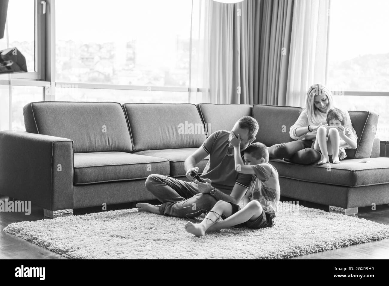 Happy family. Father, mother and children playing a video game Father and son playing video games together on the floor Stock Photo