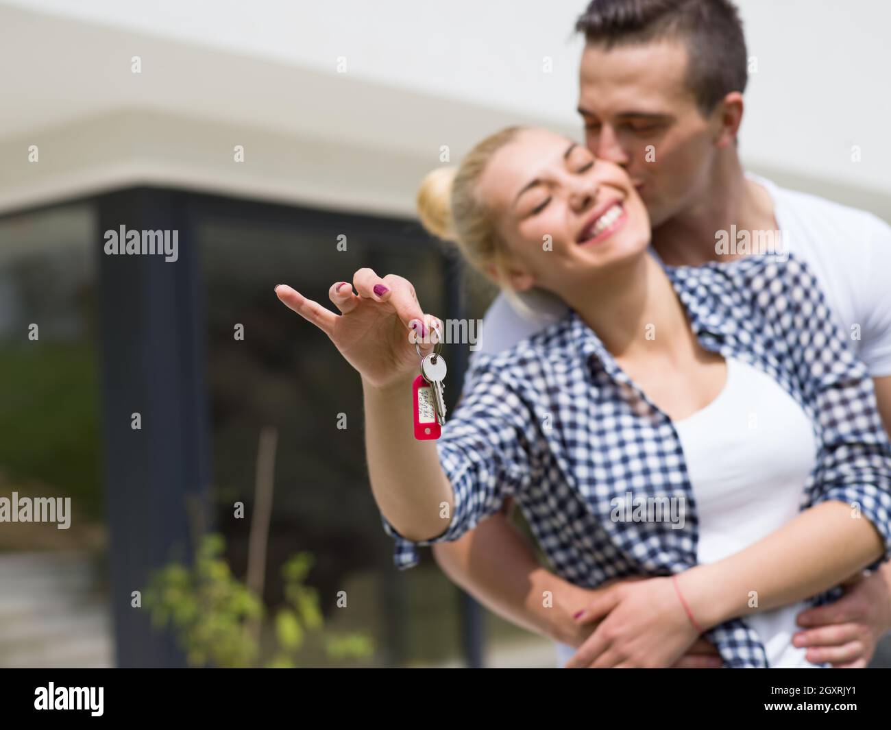 Portrait of a happy young couple hugging in front of their new luxury ...