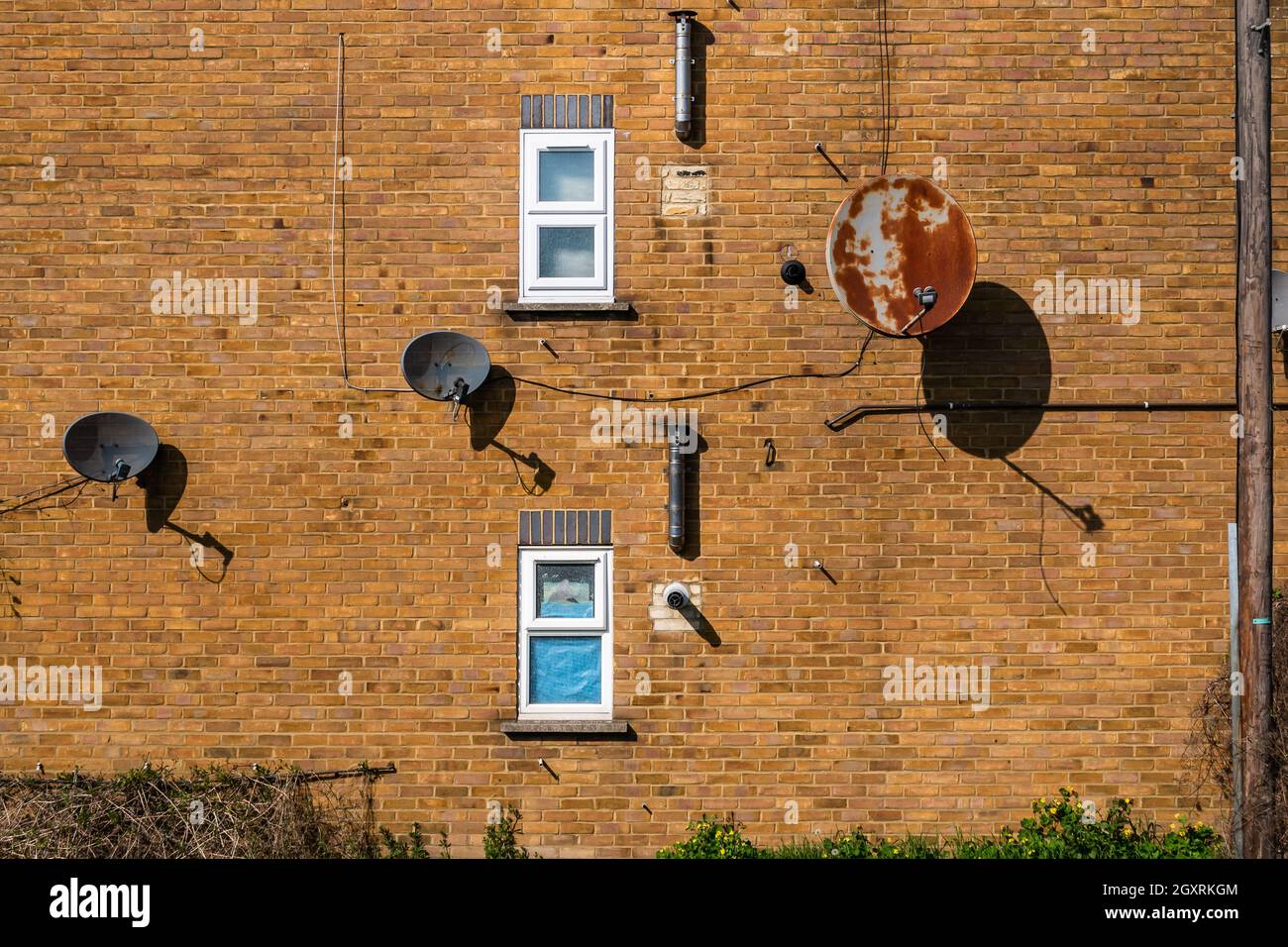 Three old satellite dishes mounted to the outside brick wall with two