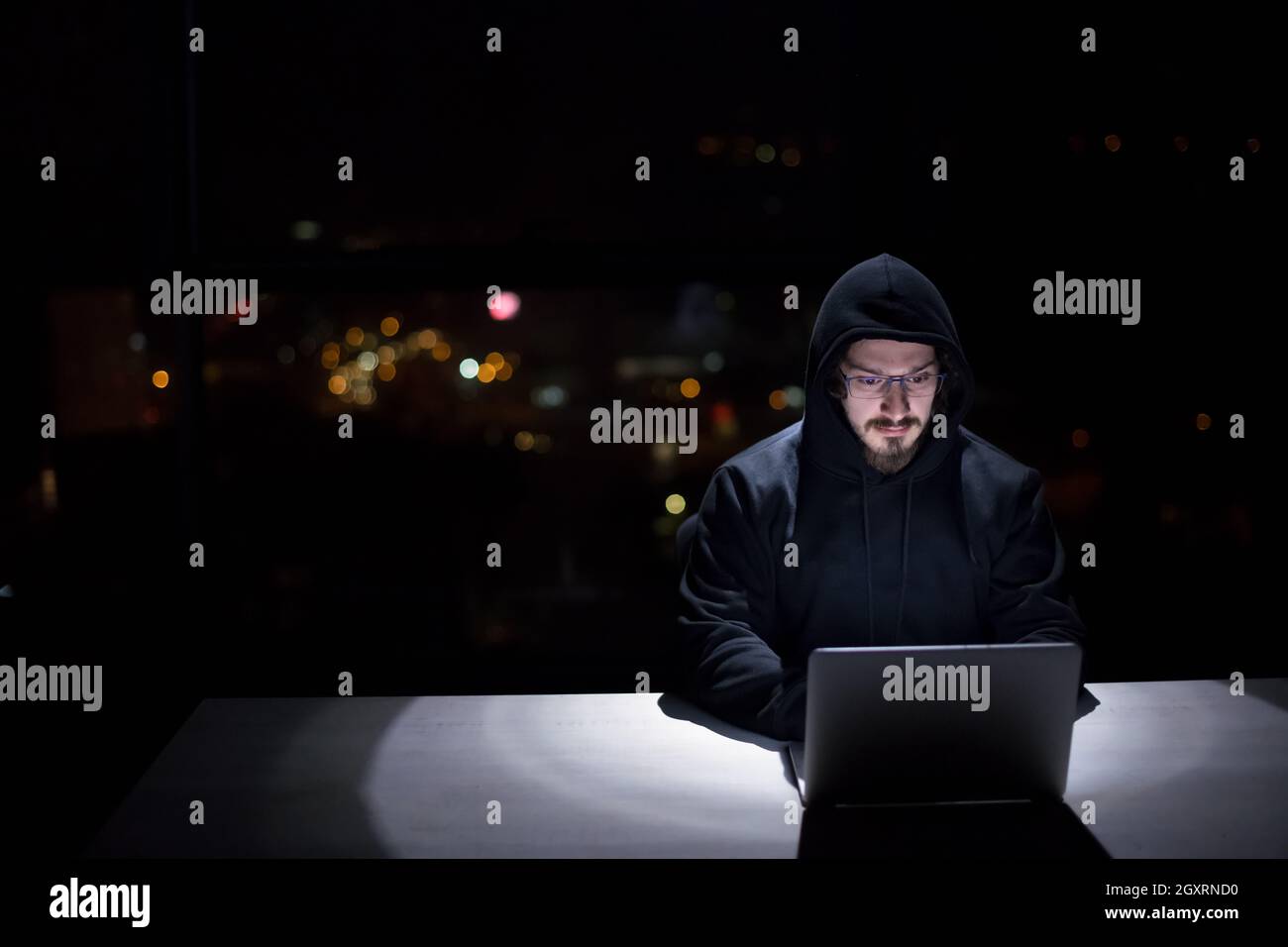 Young talented hacker using laptop computer while working in dark ...