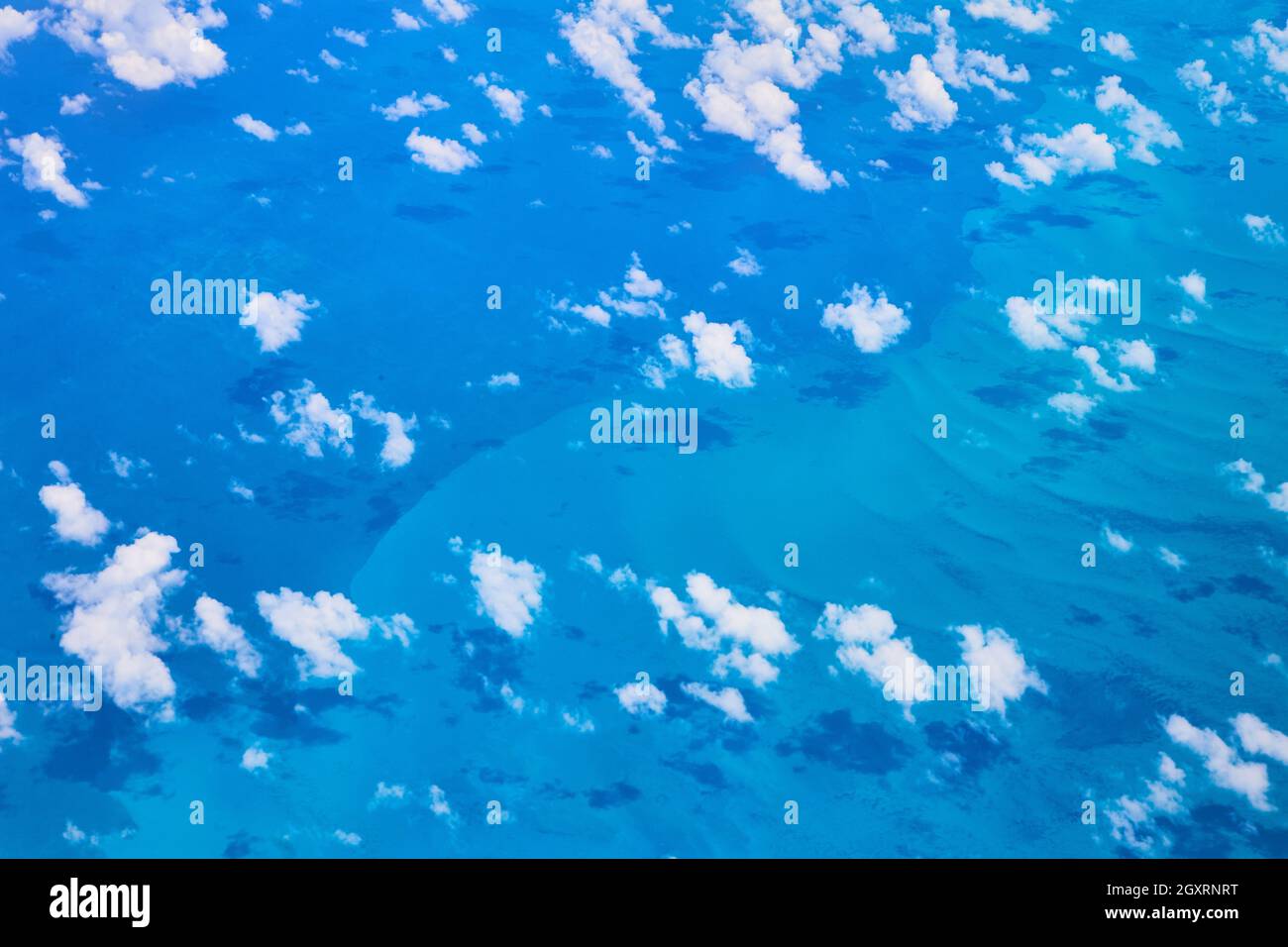 Airplane view of clouds casting shadows against the ocean water Stock Photo