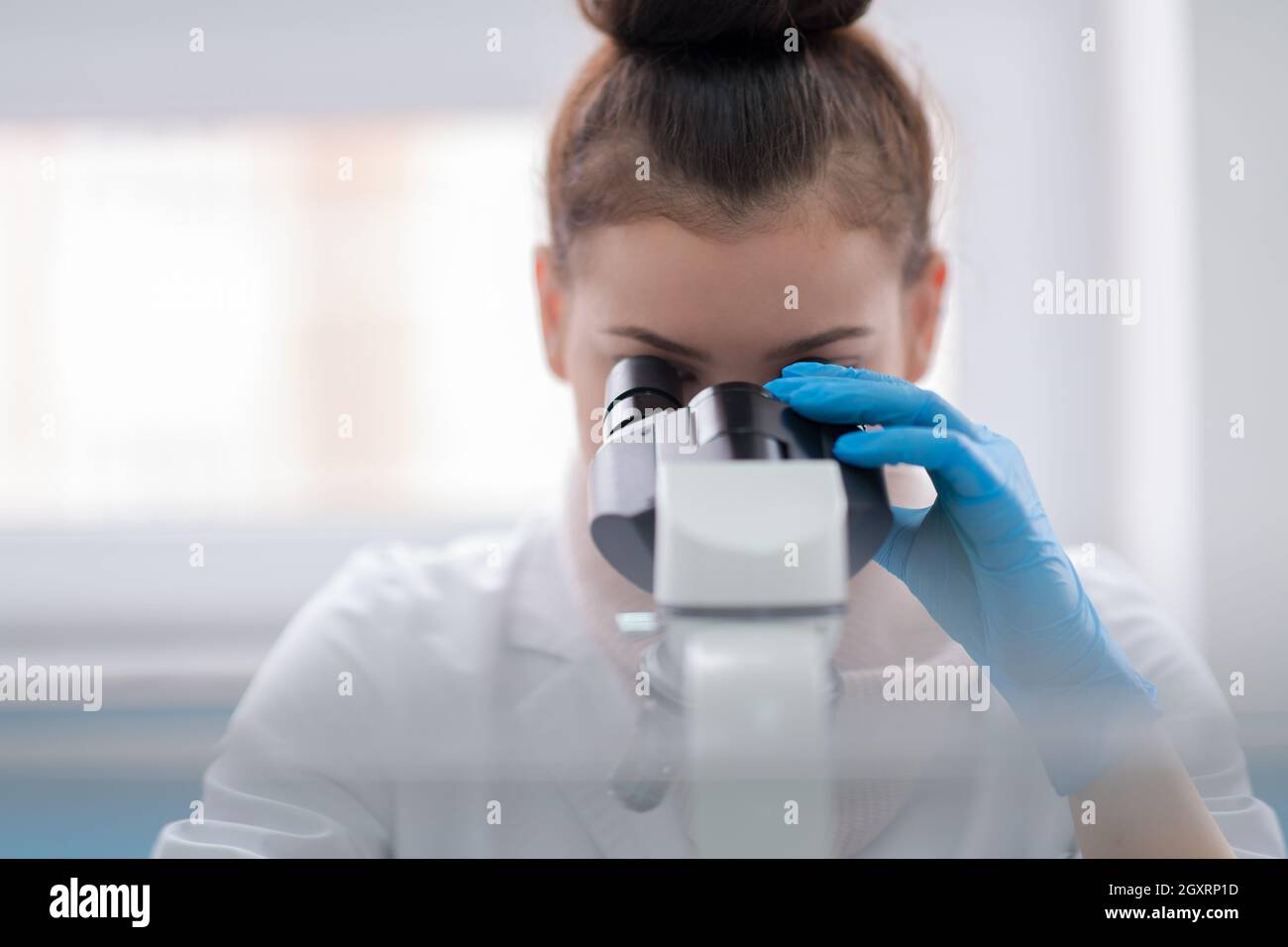 Young female student scientist looking through a microscope while doing some research in the laboratory Stock Photo