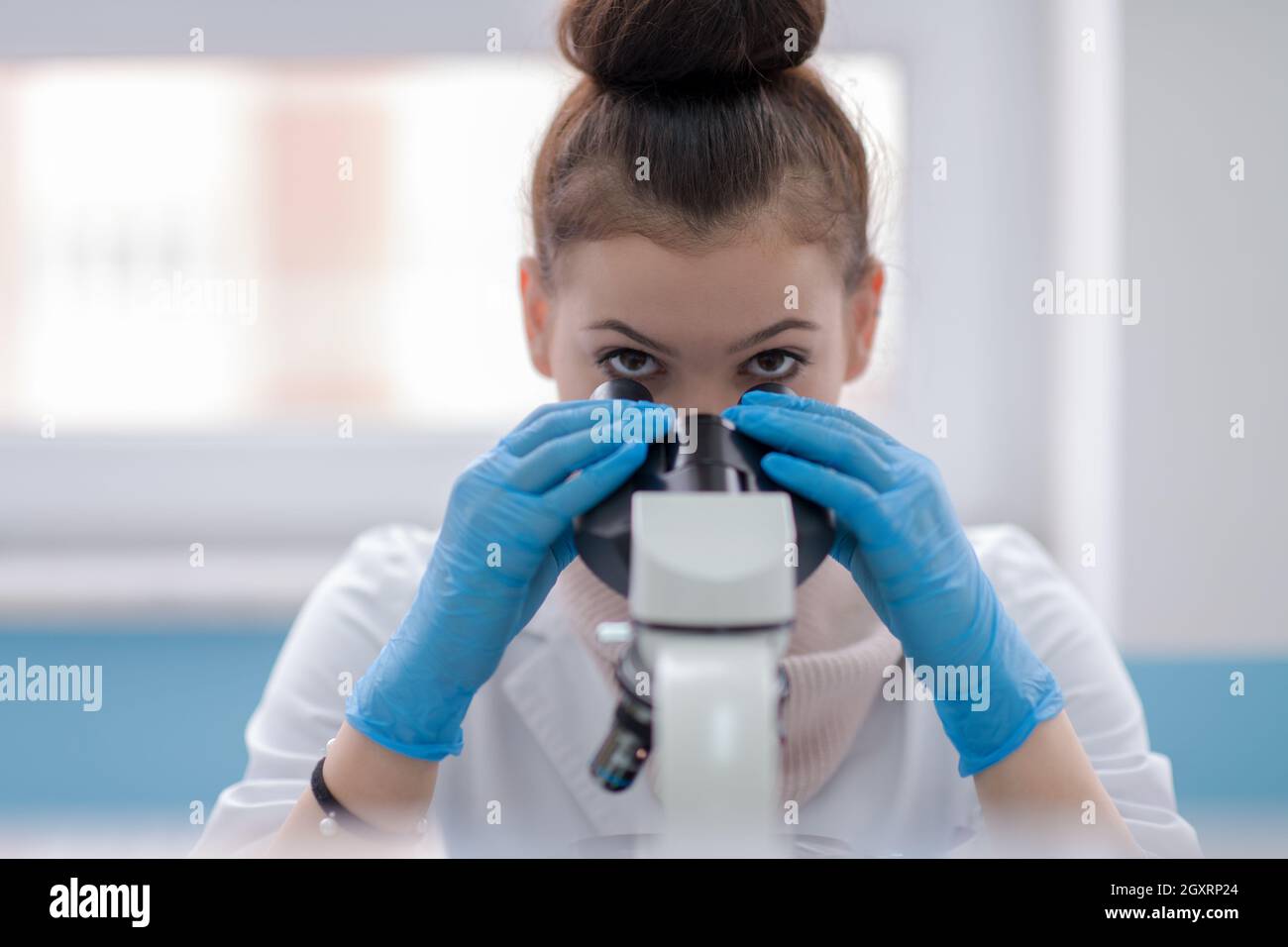 Young female student scientist looking through a microscope while doing some research in the laboratory Stock Photo