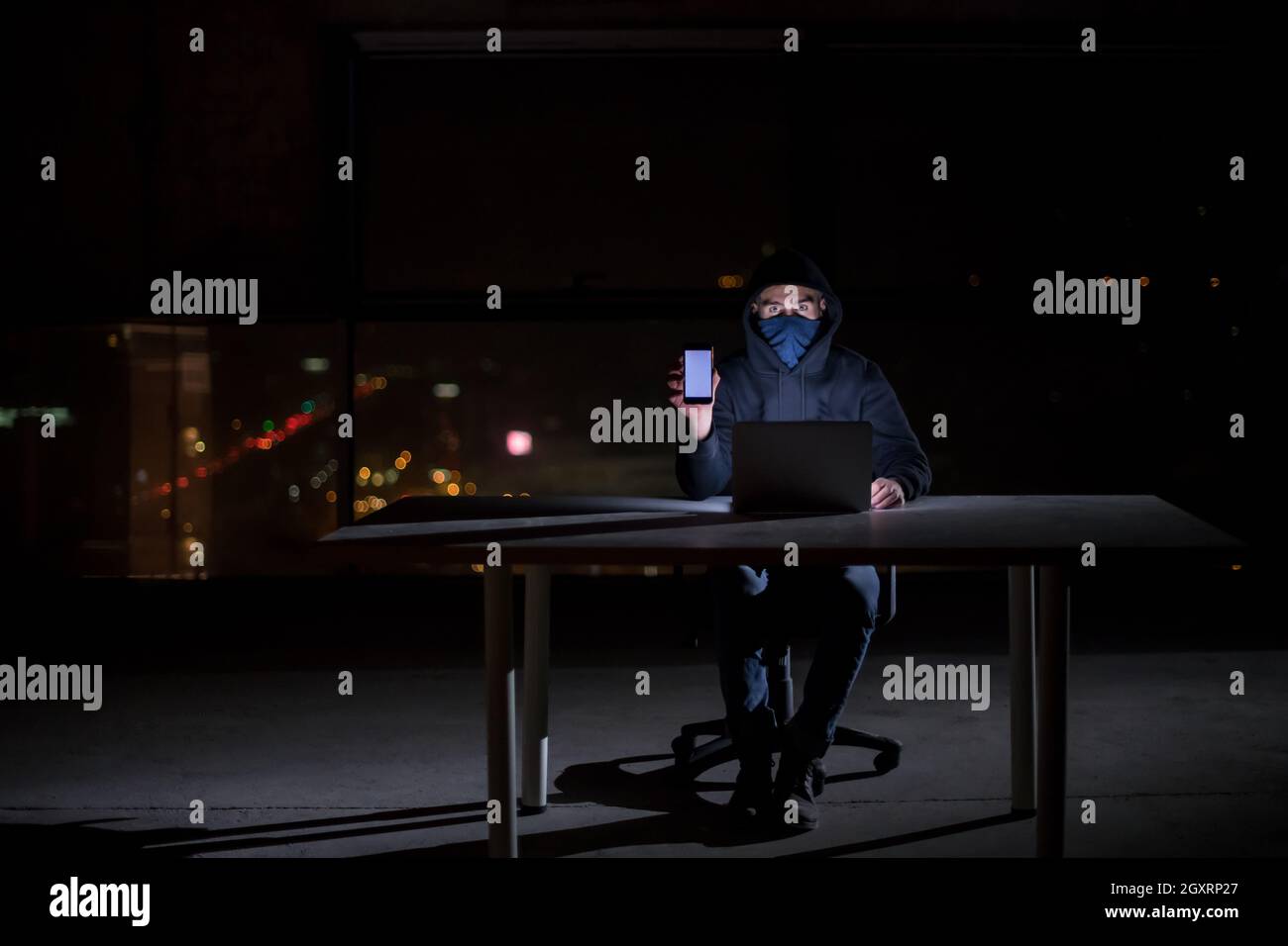 Young talented hacker using laptop computer while working in dark ...