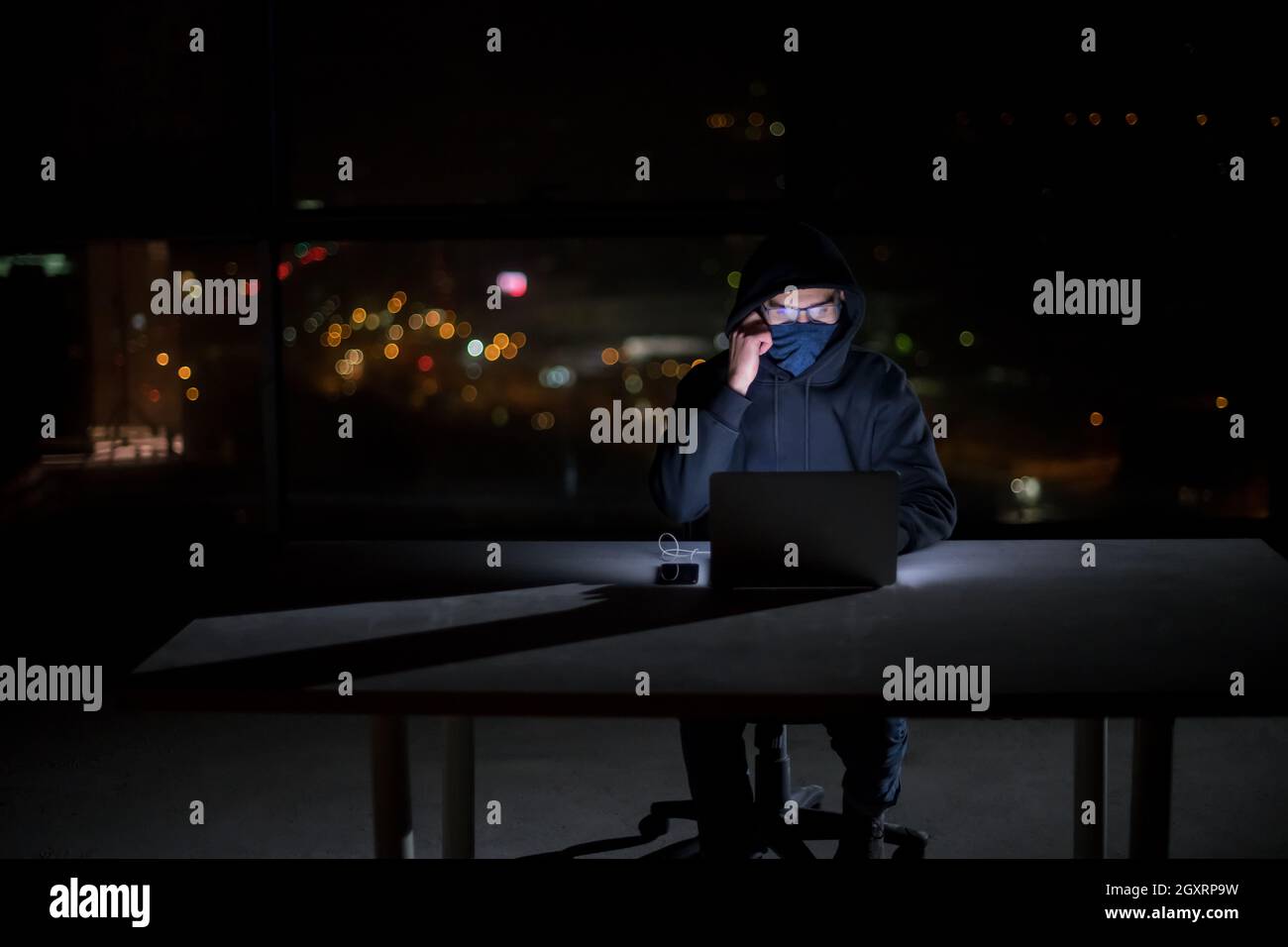 Young talented hacker using laptop computer while working in dark ...