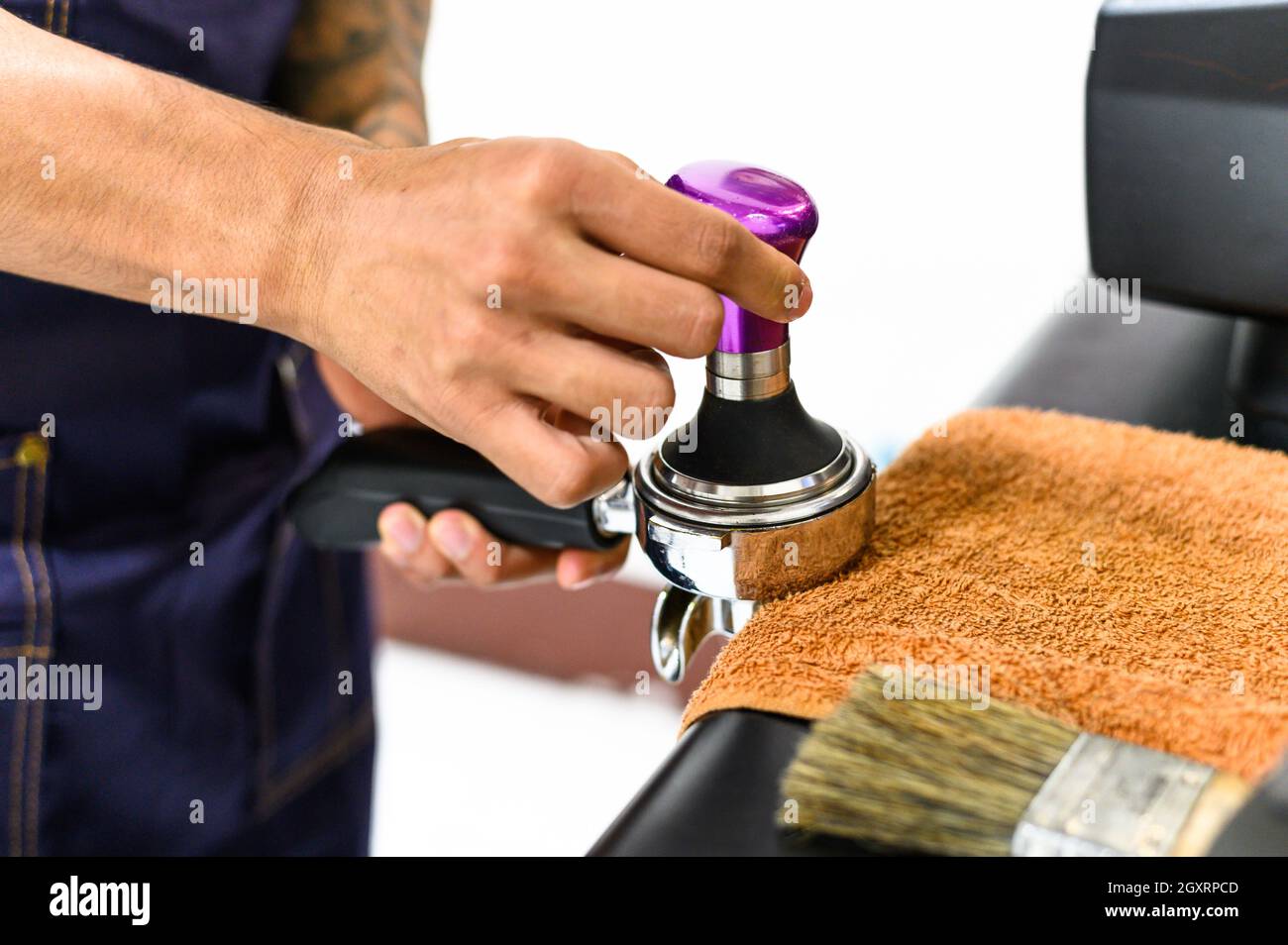 Barista squeezes coffee grounds with tamper to a good level Stock Photo