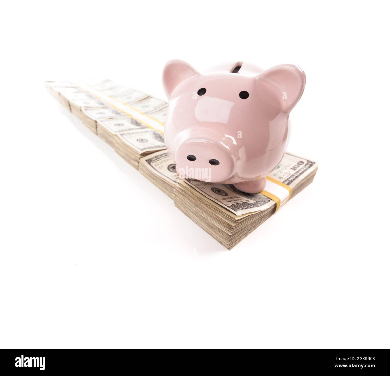 Pink Piggy Bank on Row of Hundreds of Dollars Stacks Isolated on a White Background. Stock Photo