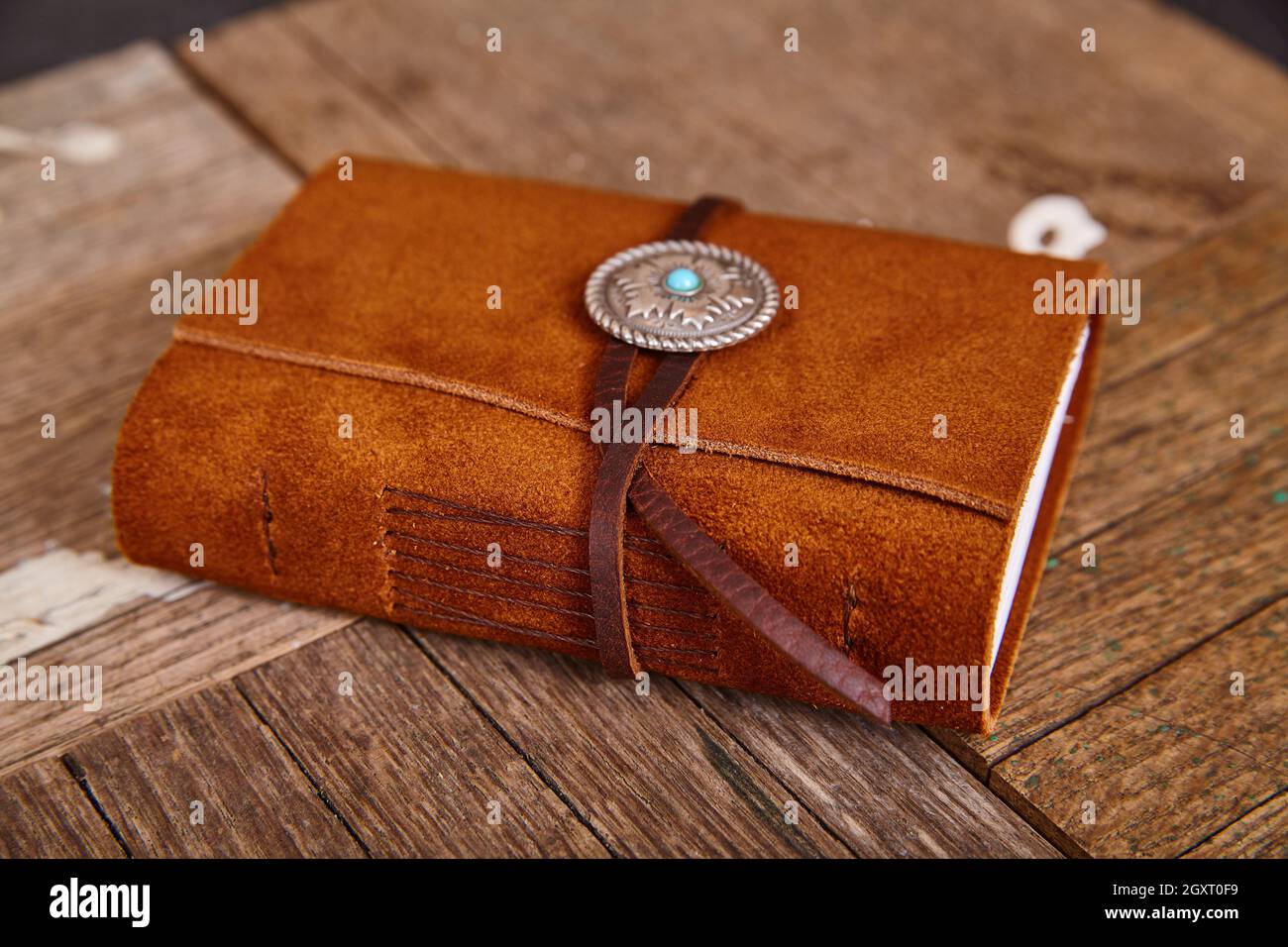 Small closed leather journal with concho and thread on wood boards Stock Photo
