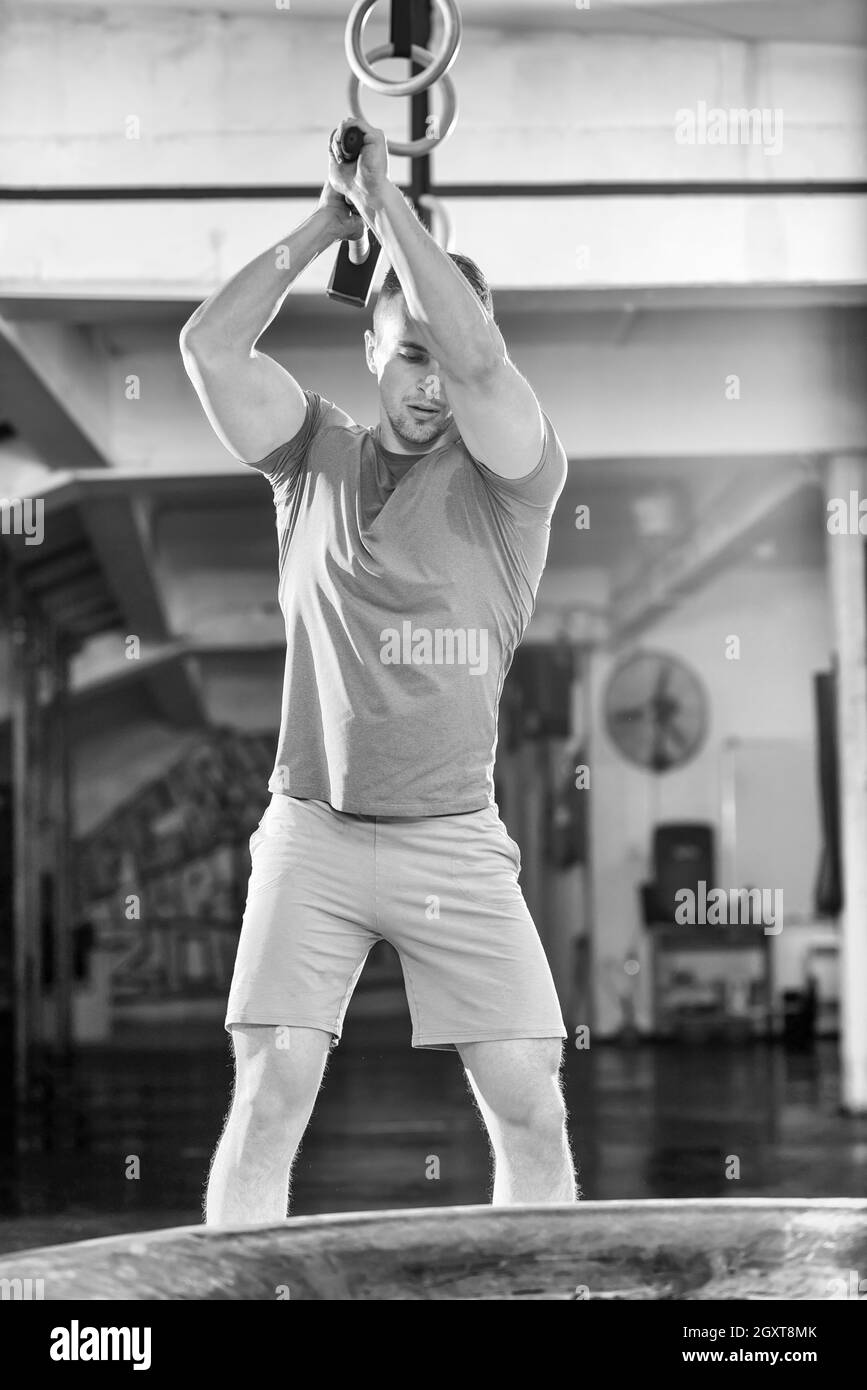 Sledgehammer Tire Hits young muscular man workout at gym with hammer