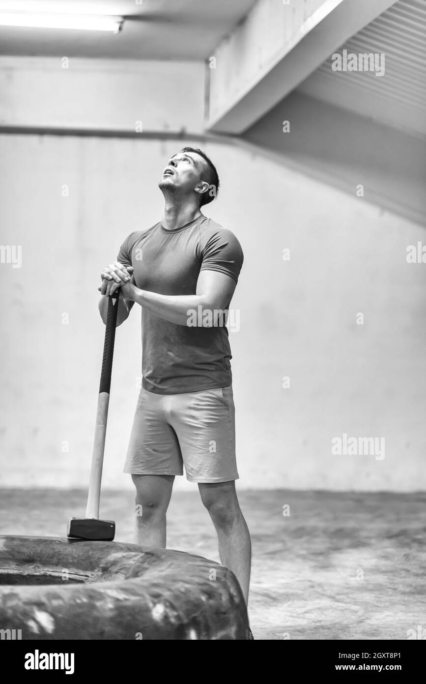 Sledgehammer Tire Hits young muscular man workout at gym with hammer and tractor tire Stock