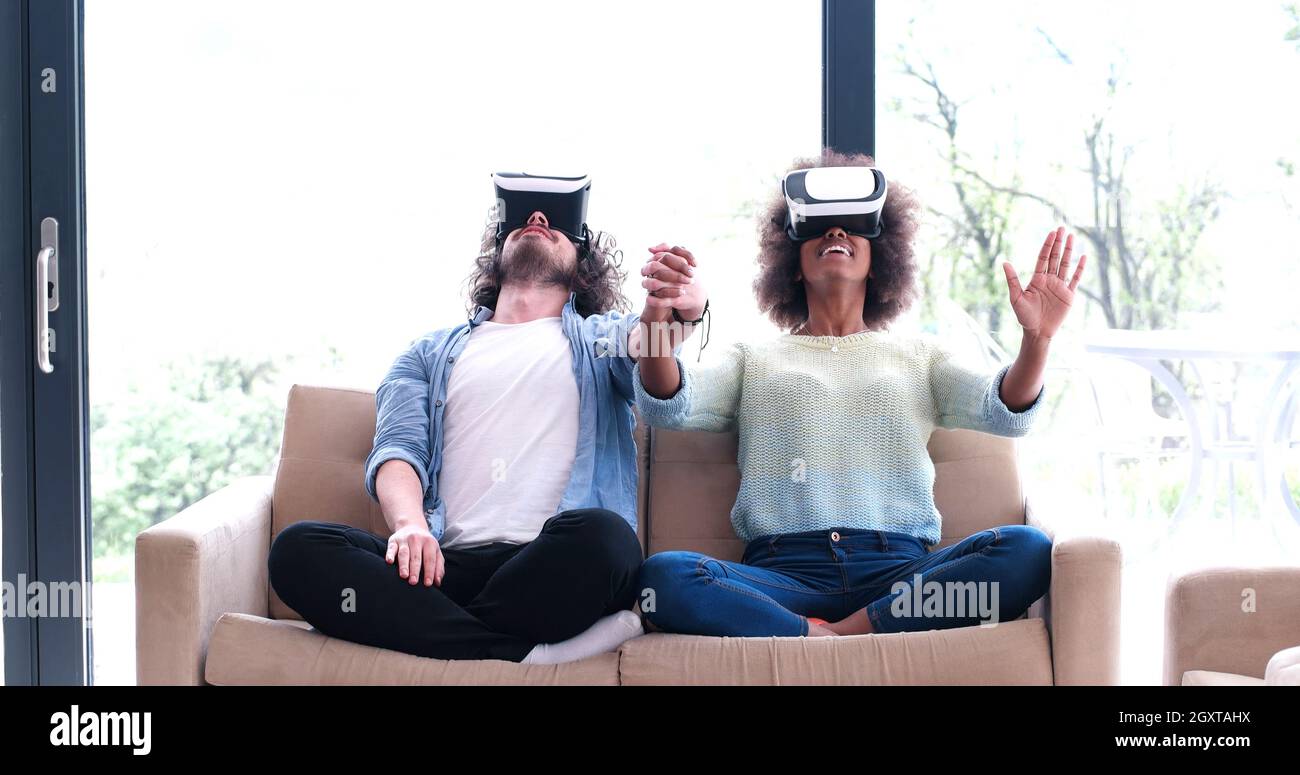 Multiethnic Couple using virtual reality headset in living room at home ...