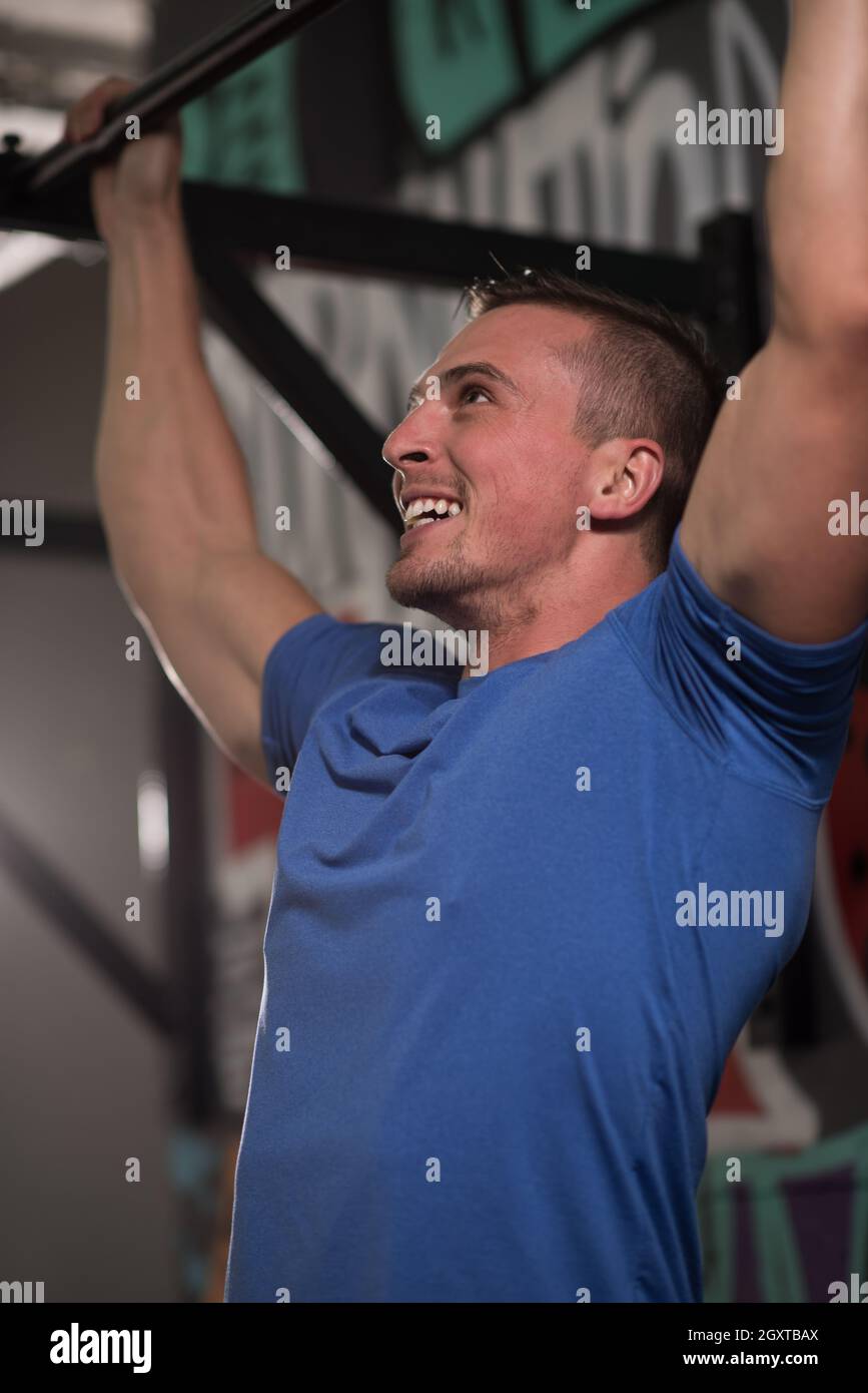 strong young man doing pull ups on a bar in a gym Stock Photo - Alamy