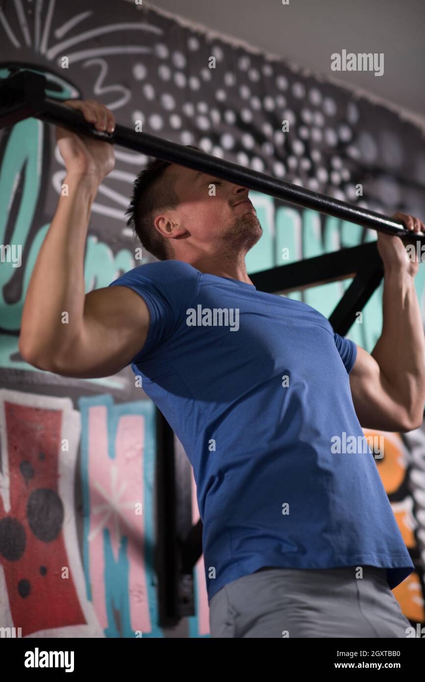 strong young man doing pull ups on a bar in a gym Stock Photo - Alamy
