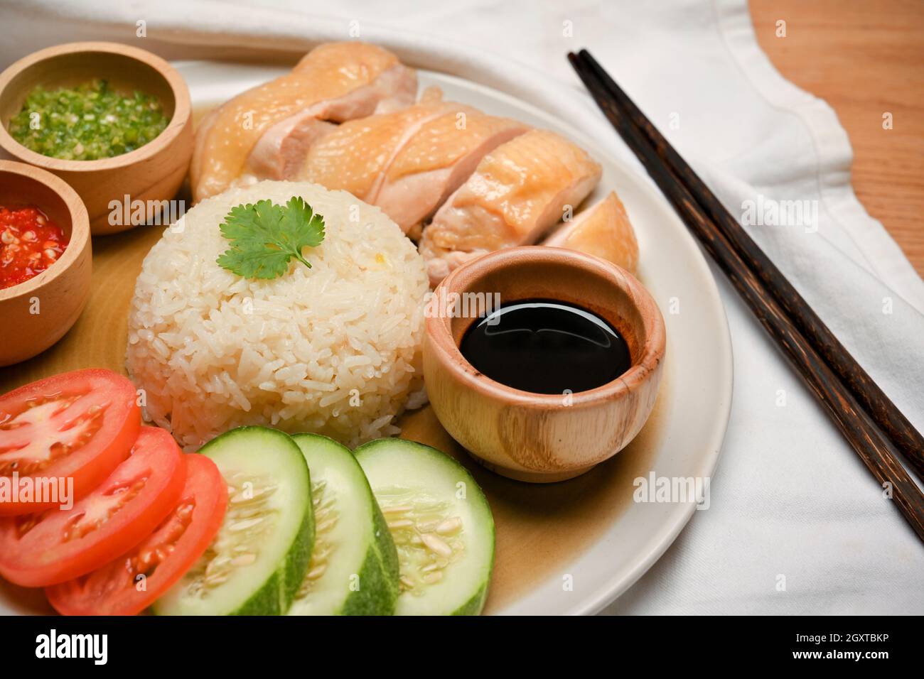 Closeup Hainanese chicken rice, poached chicken, seasoned rice, chilli sauces, soybean sauce