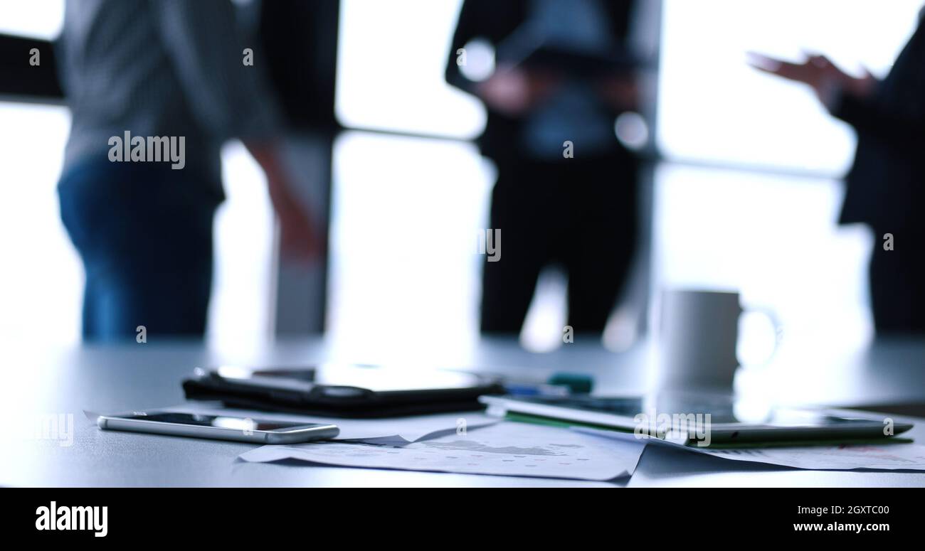Devices on table with business people in background in modern office building Stock Photo