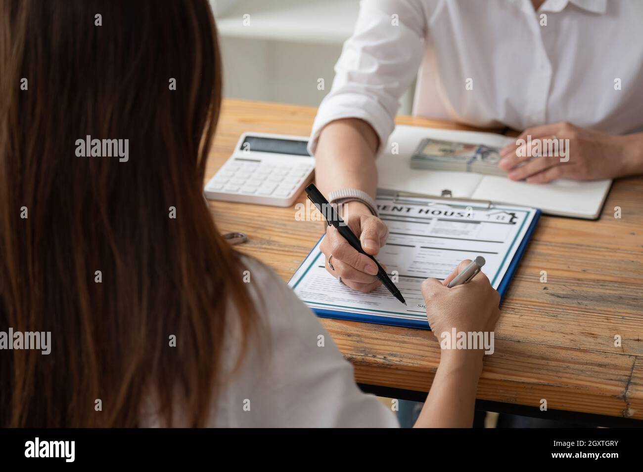 close up view hands of businessman signing leasing home documents and have a apartment keys on paperwork. house rental concept Stock Photo