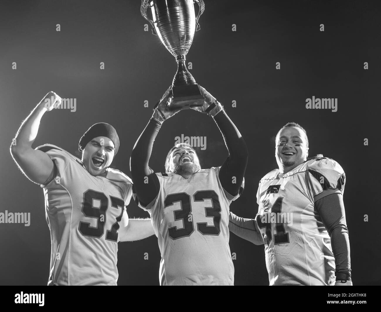 happy american football team with trophy celebrating victory on night