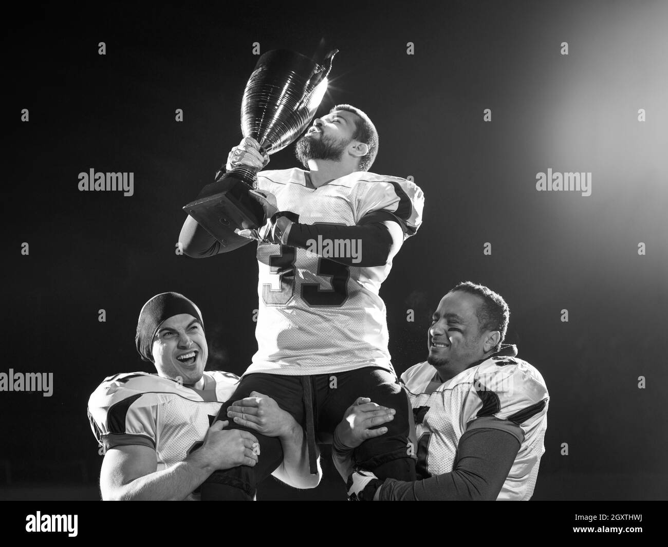 happy american football team with trophy celebrating victory on night