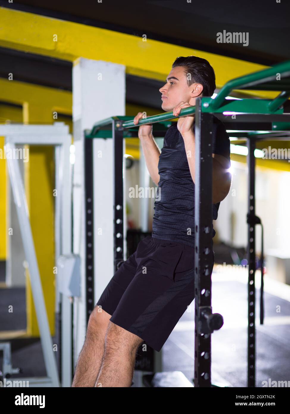young muscular man doing pull ups on the horizontal bar as part of ...