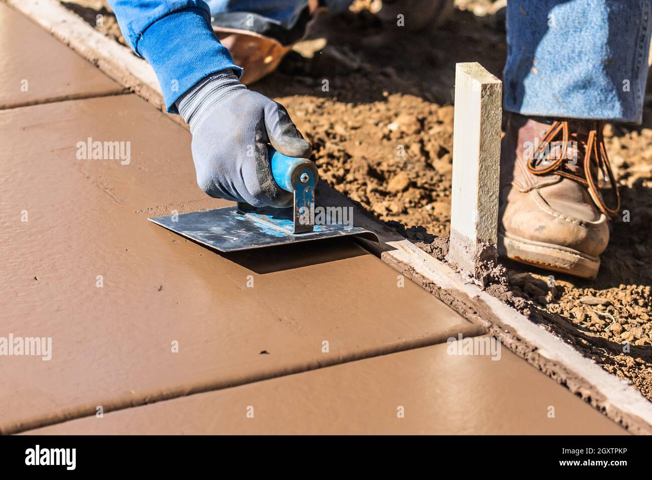 Construction Worker Using Hand Groover On Wet Cement Forming Coping