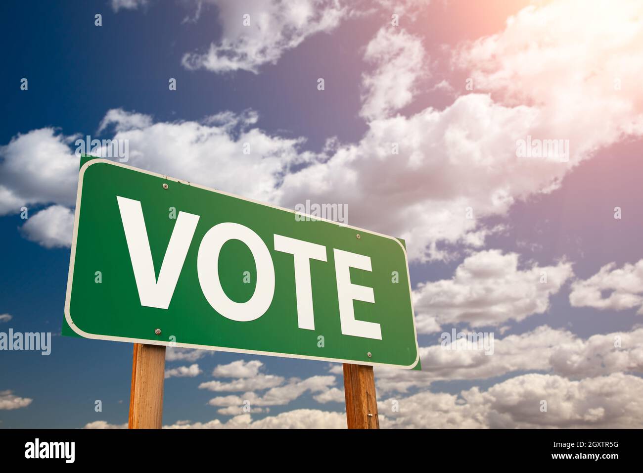 Vote Green Road Sign Over Dramatic Clouds and Sky. Stock Photo