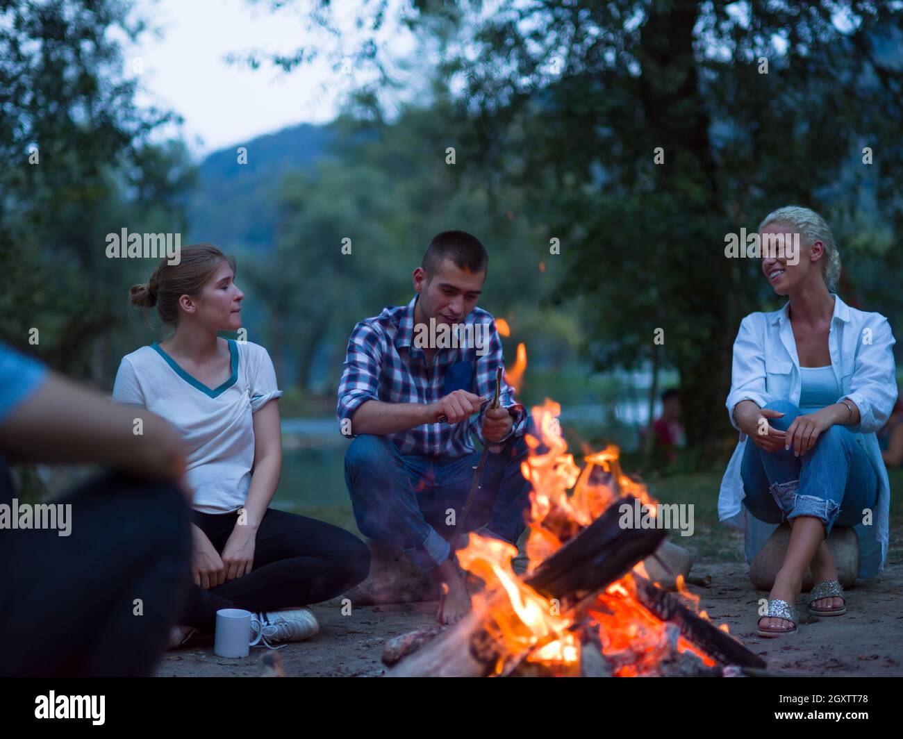 a group of happy young friends relaxing and enjoying summer evening ...