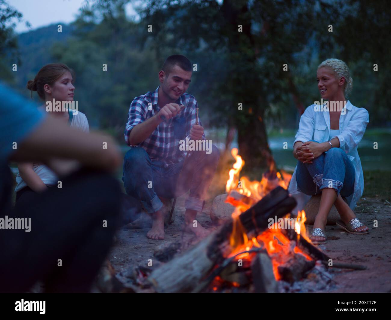 a group of happy young friends relaxing and enjoying summer evening ...