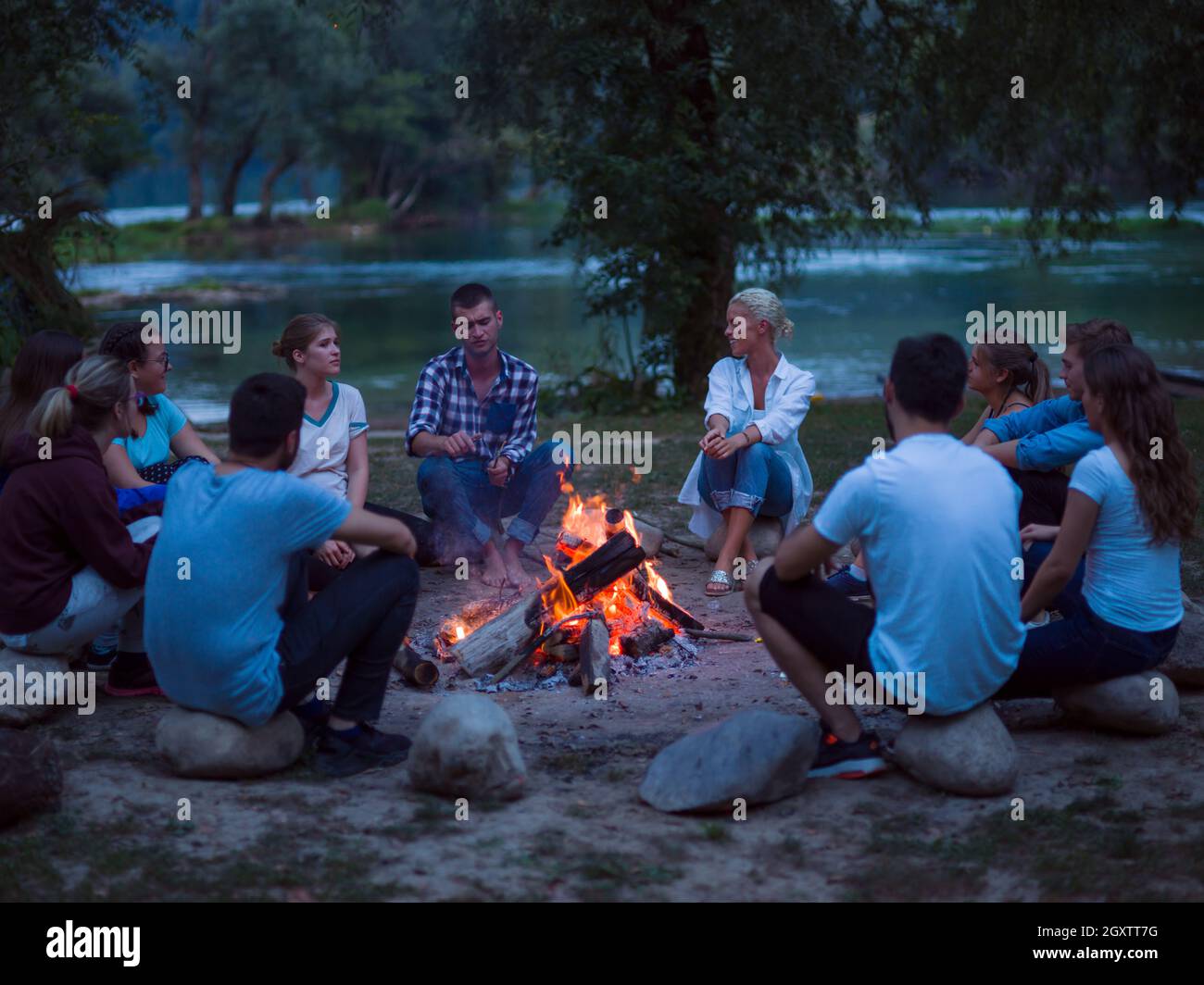 a group of happy young friends relaxing and enjoying summer evening ...