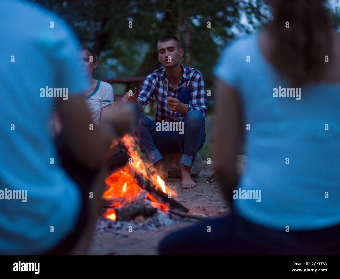 a group of happy young friends relaxing and enjoying summer evening ...