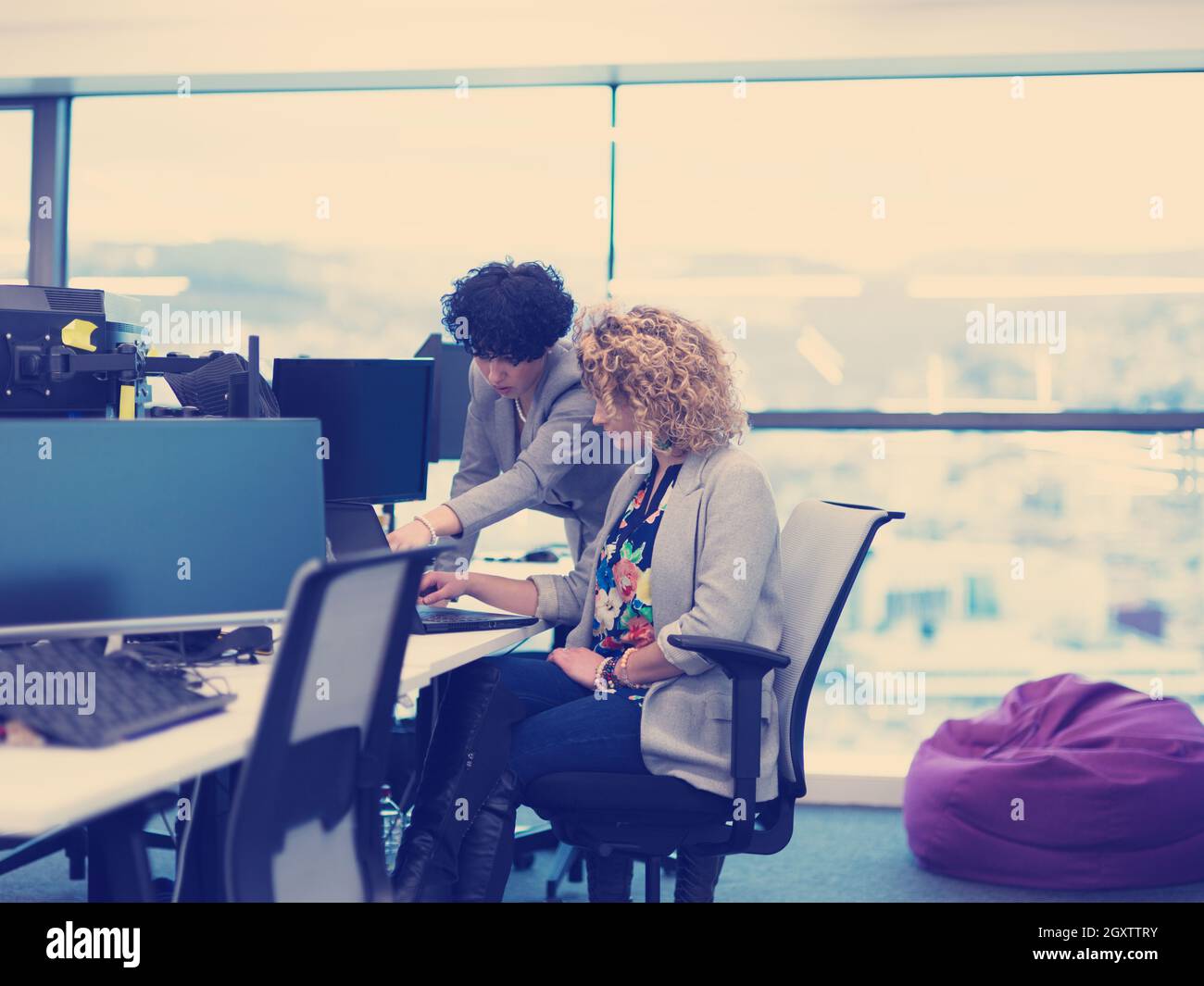group of young female software developers using laptop and desktop computers while writing programming code at modern creative startup office Stock Photo