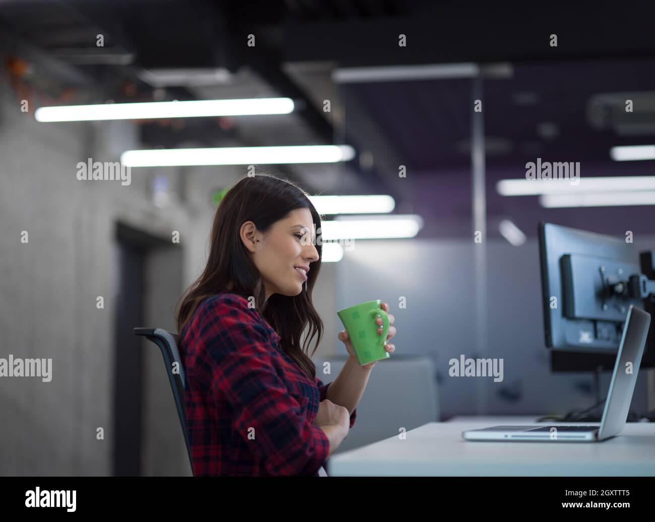 young female software developer using laptop computer while writing programming code at modern creative startup office Stock Photo