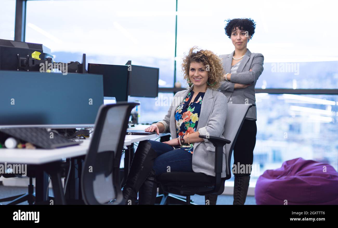 group of young female software developers using laptop and desktop computers while writing programming code at modern creative startup office Stock Photo