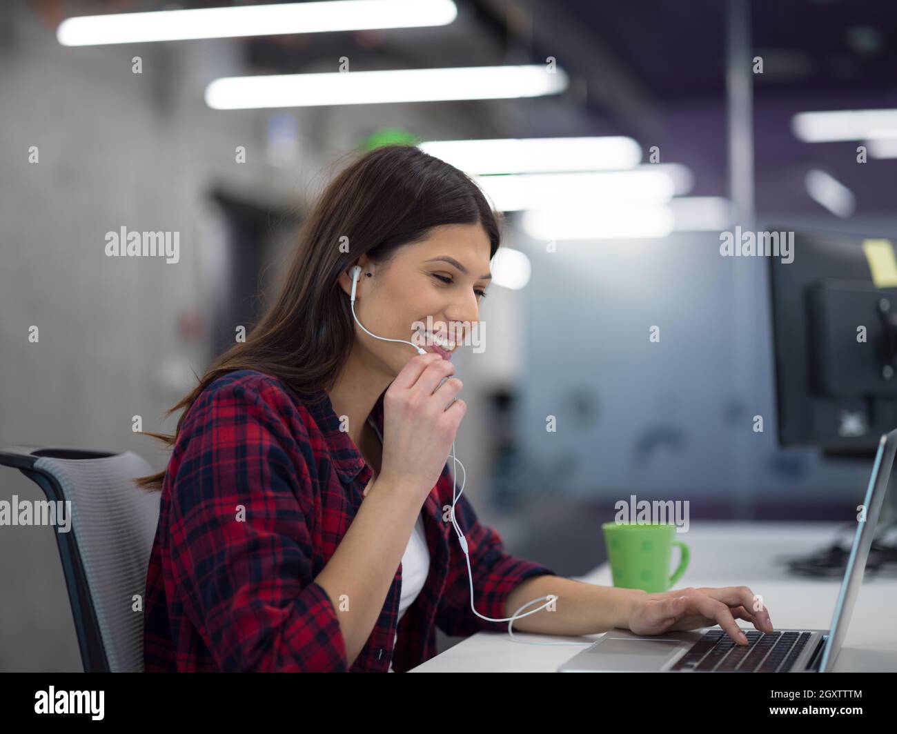 young female software developer using laptop computer while writing ...
