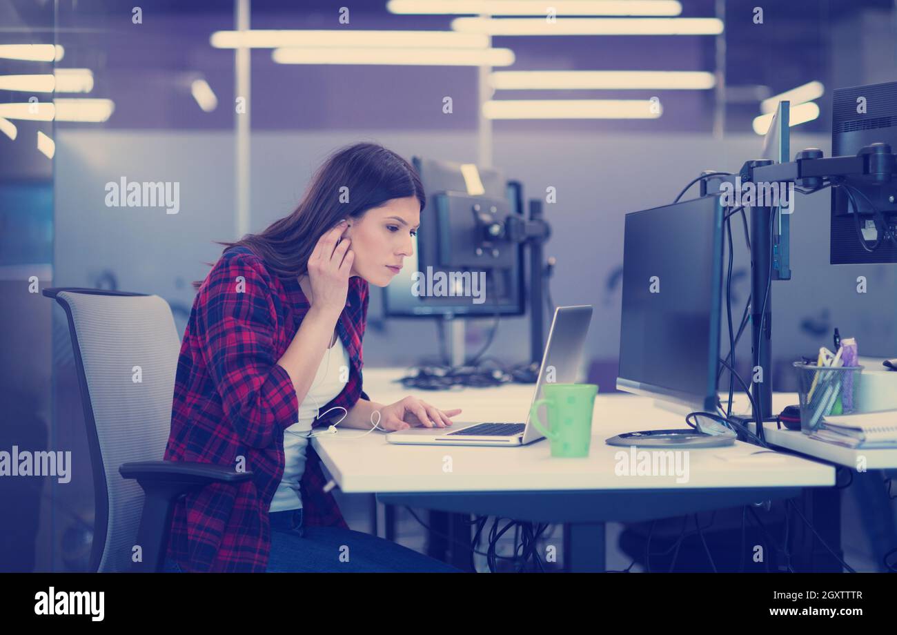 young female software developer using laptop computer while writing programming code at modern creative startup office Stock Photo