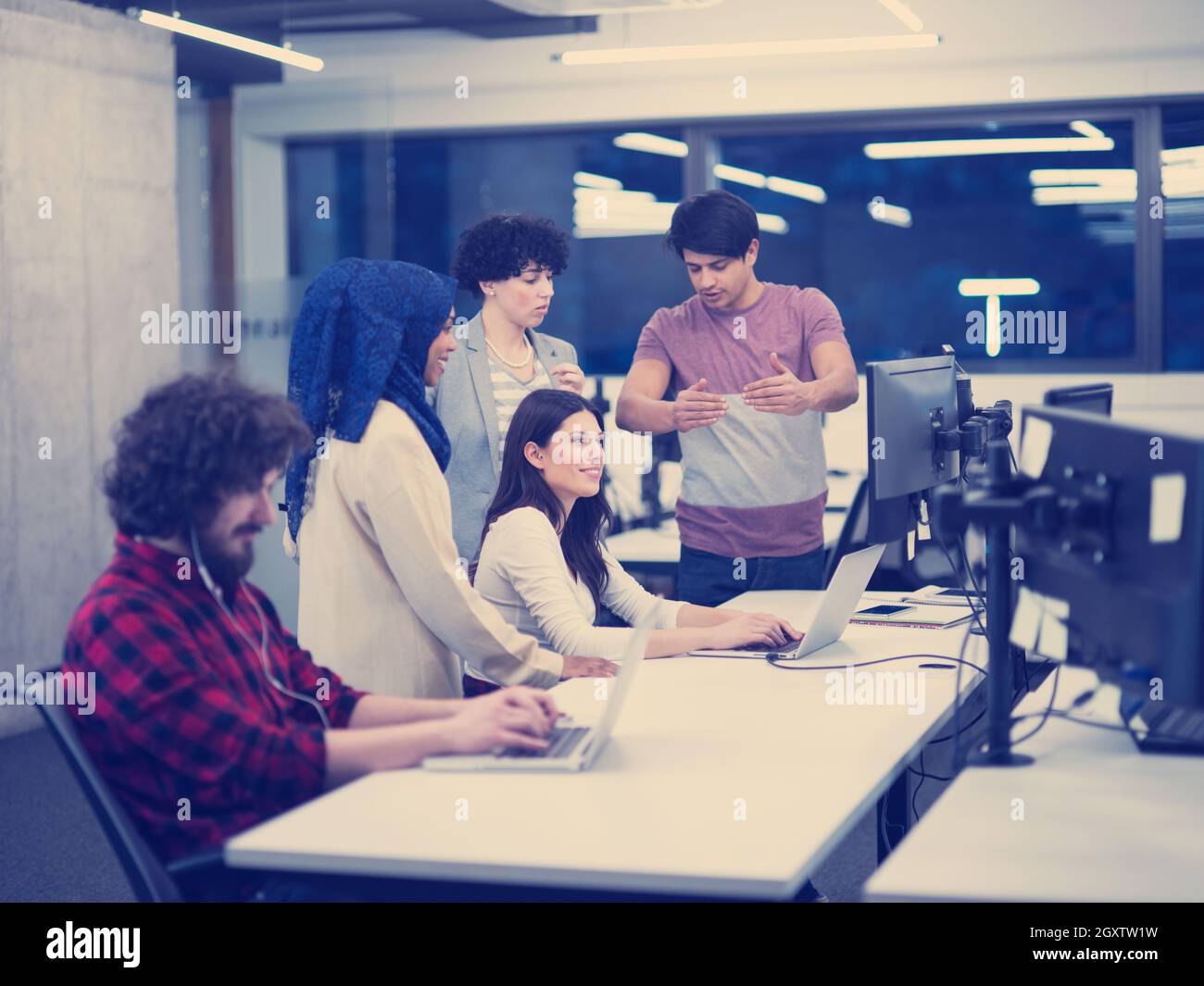 young multiethnics business team of software developers working together using laptop and desktop computers while writing programming code at modern s Stock Photo
