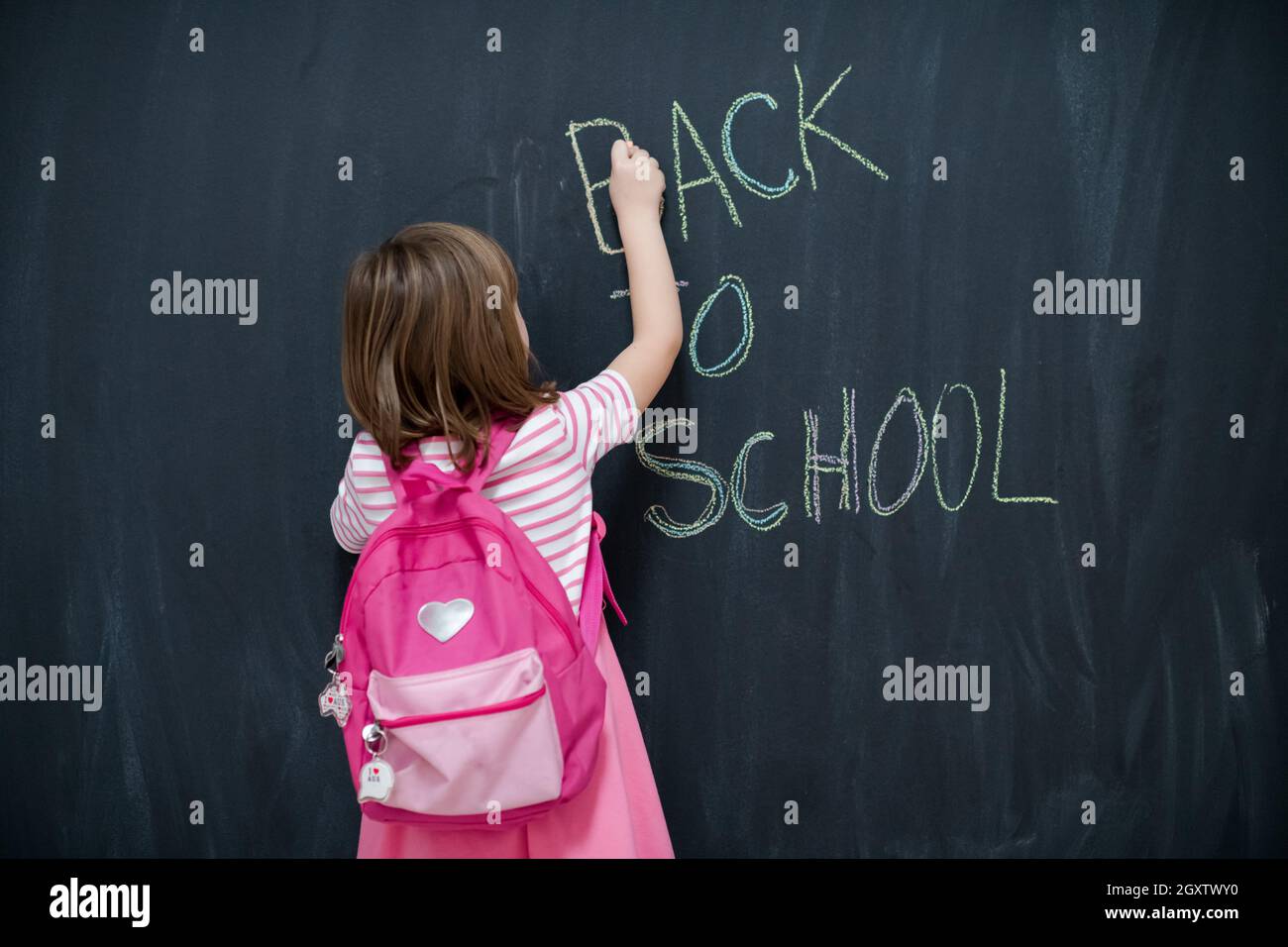 Happy school girl child with backpack writing back to school on black ...