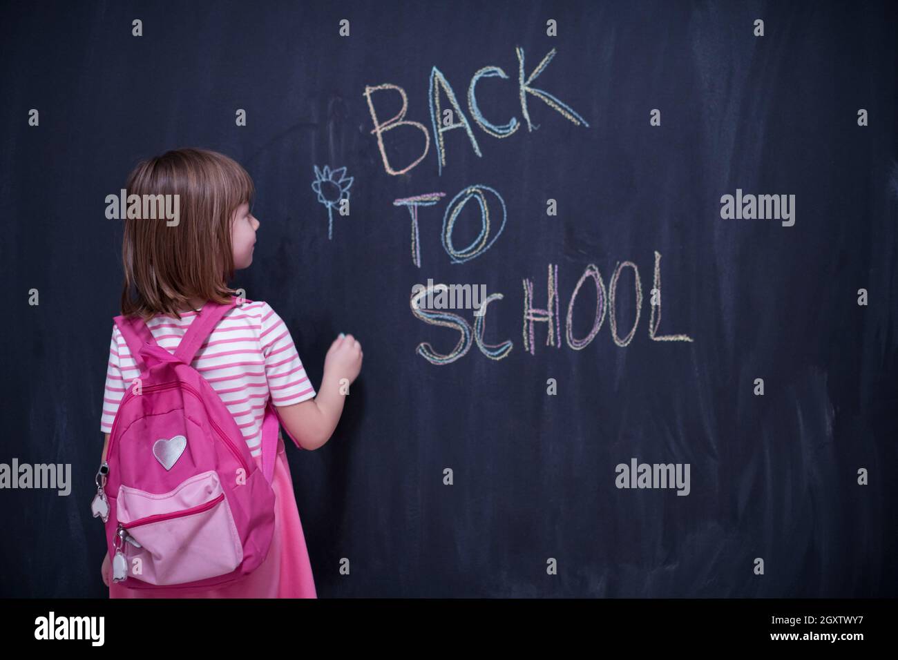 Happy school girl child with backpack writing back to school on black ...
