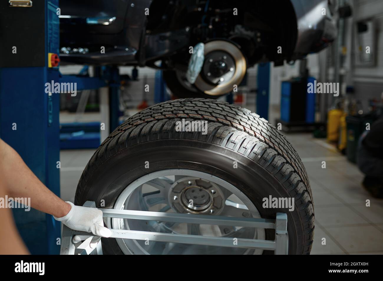 Male mechanic fixes problem with wheel, car service. Vehicle repairing