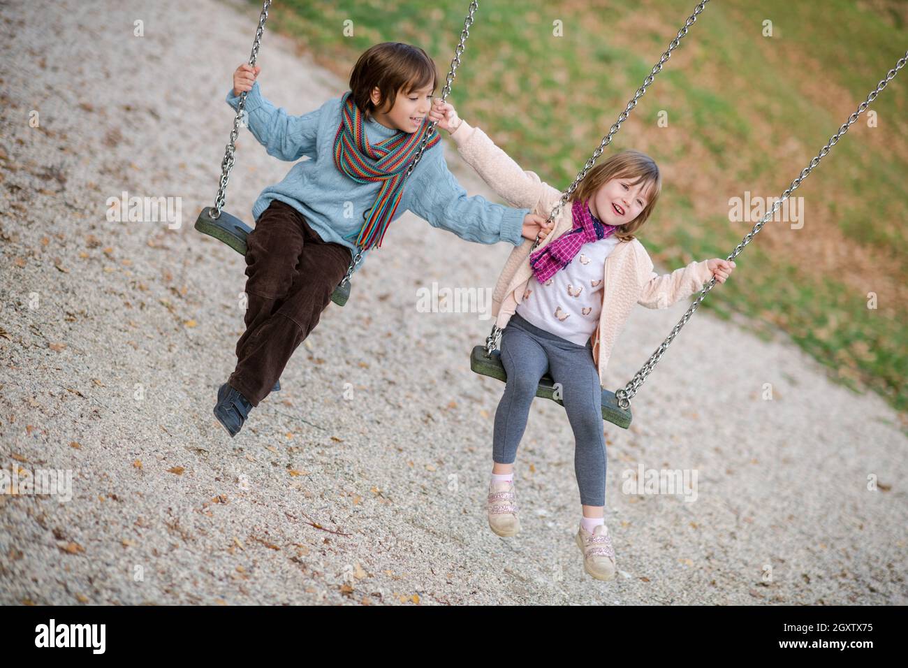 cheerful children are having fun on a swing little brother and sister ...