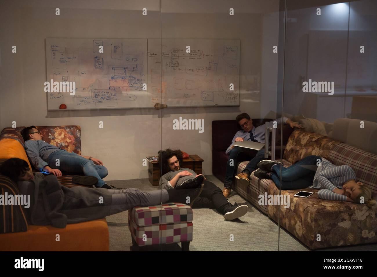 group of young casual software developer sleeping on  sofa during a work break in creative startup office Stock Photo