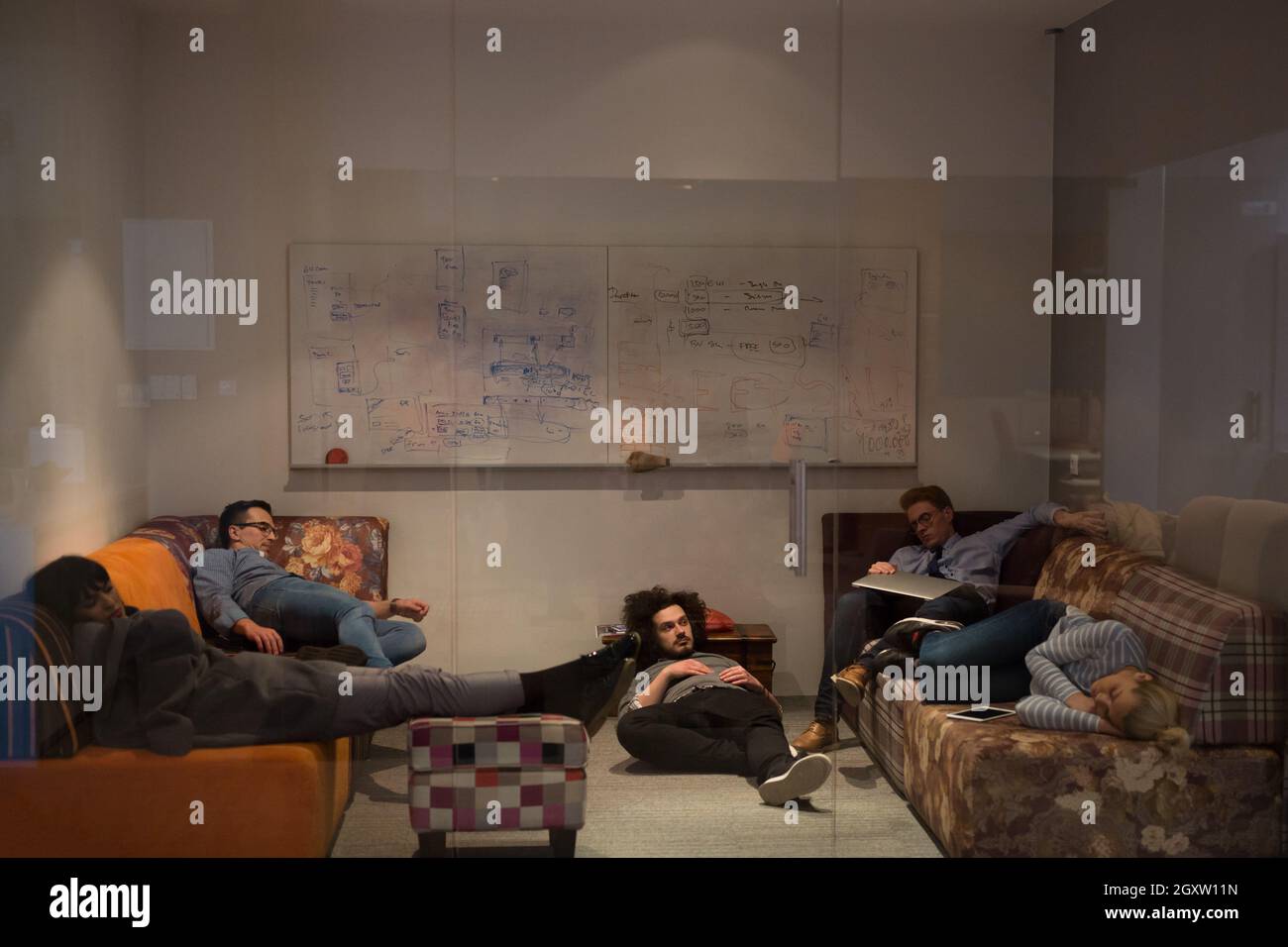 group of young casual software developer sleeping on  sofa during a work break in creative startup office Stock Photo