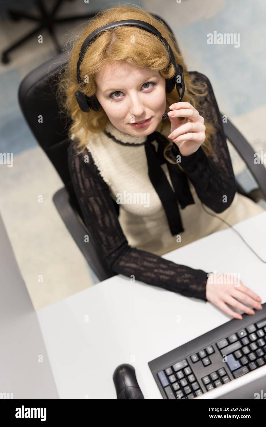 top view of a young smiling female call centre operator doing her job with a headset Stock Photo
