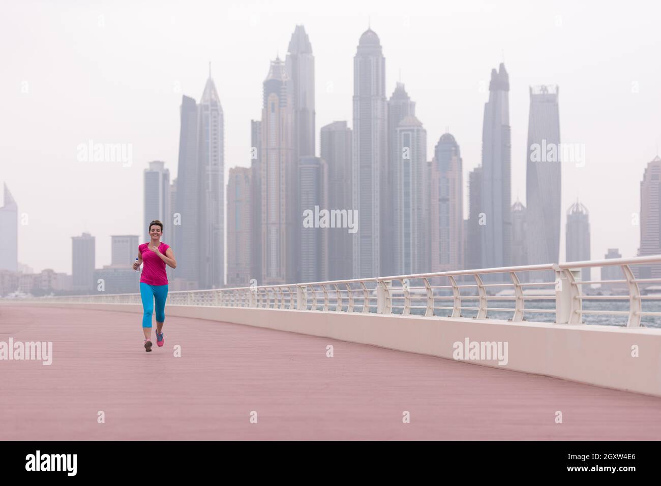 very active young beautiful woman busy running on the promenade along ...