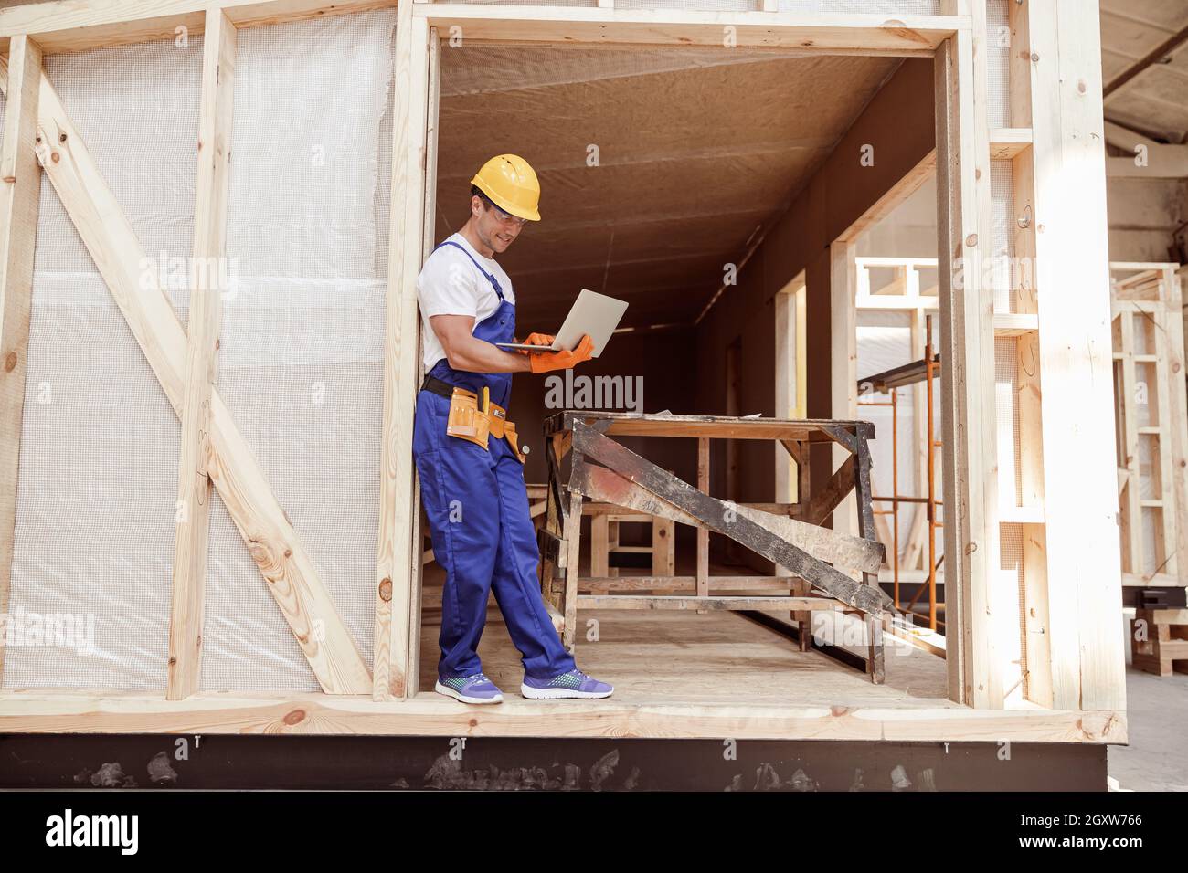 Cheerful male builder using laptop at construction site Stock Photo