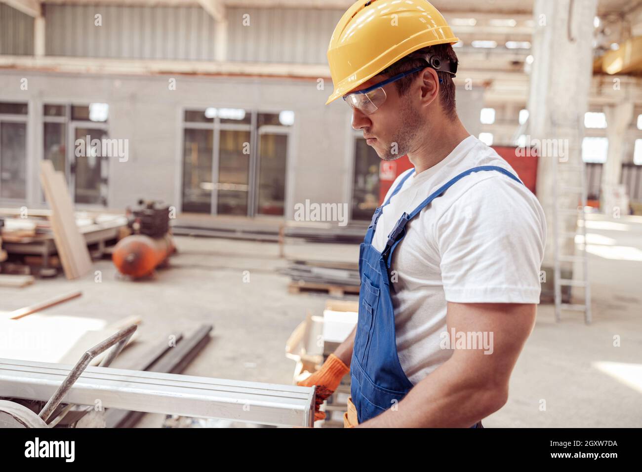 Handsome male worker using sawing machine in workshop Stock Photo