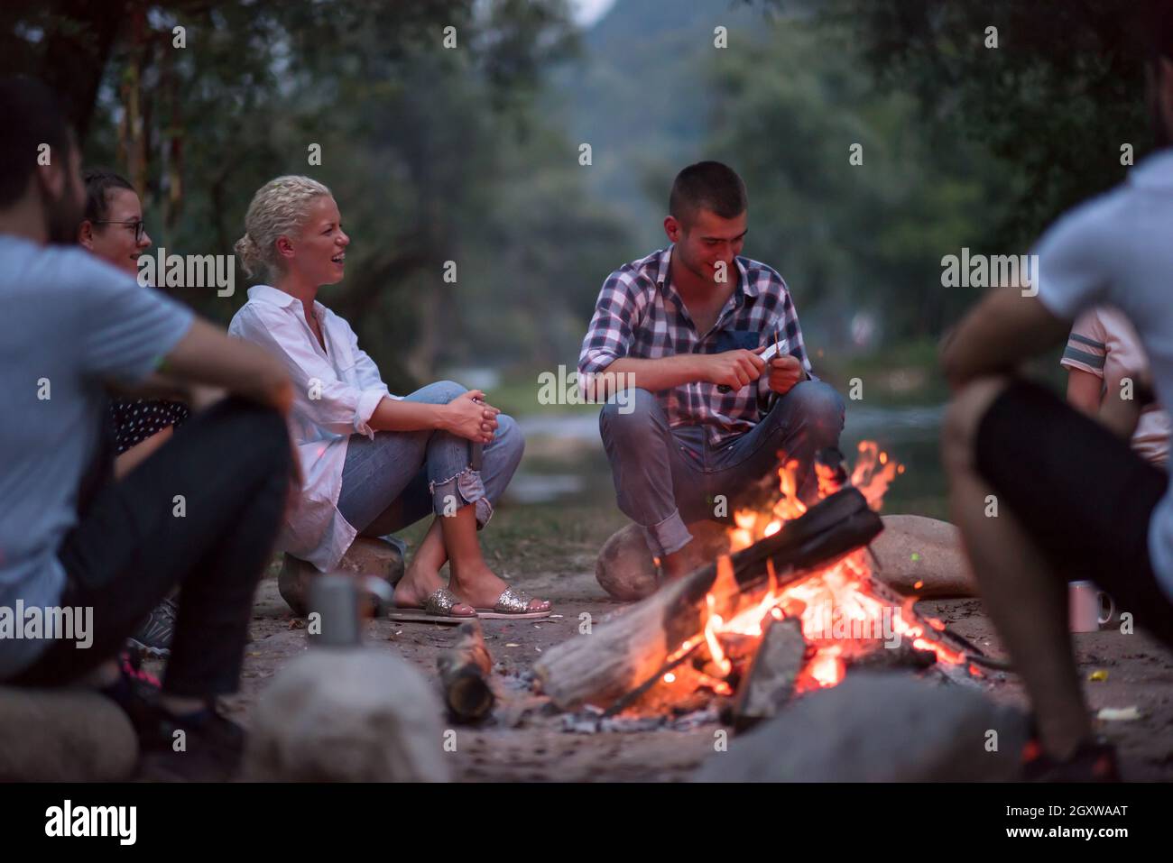 a group of happy young friends relaxing and enjoying summer evening ...