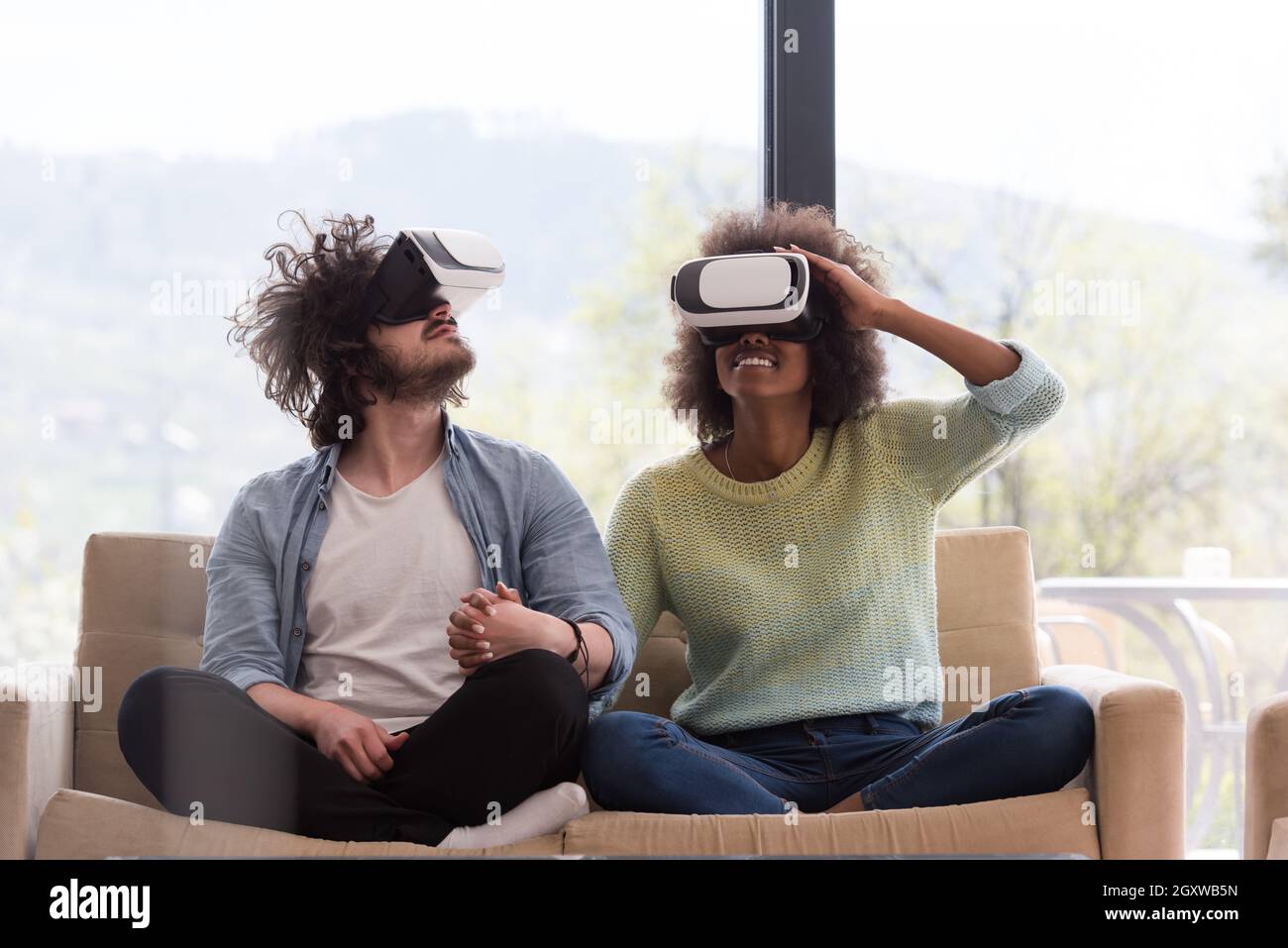 Multiethnic Couple using virtual reality headset in living room at home ...
