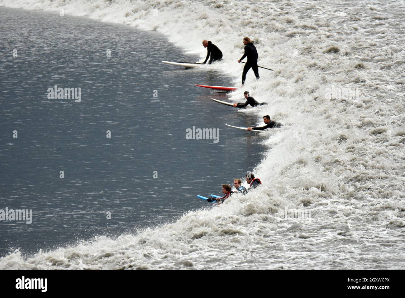 Cold water surfers ride a bore tide wave in the Turnagain Arm of the Cook Inlet, Anchorage, Alaska, USA Stock Photo