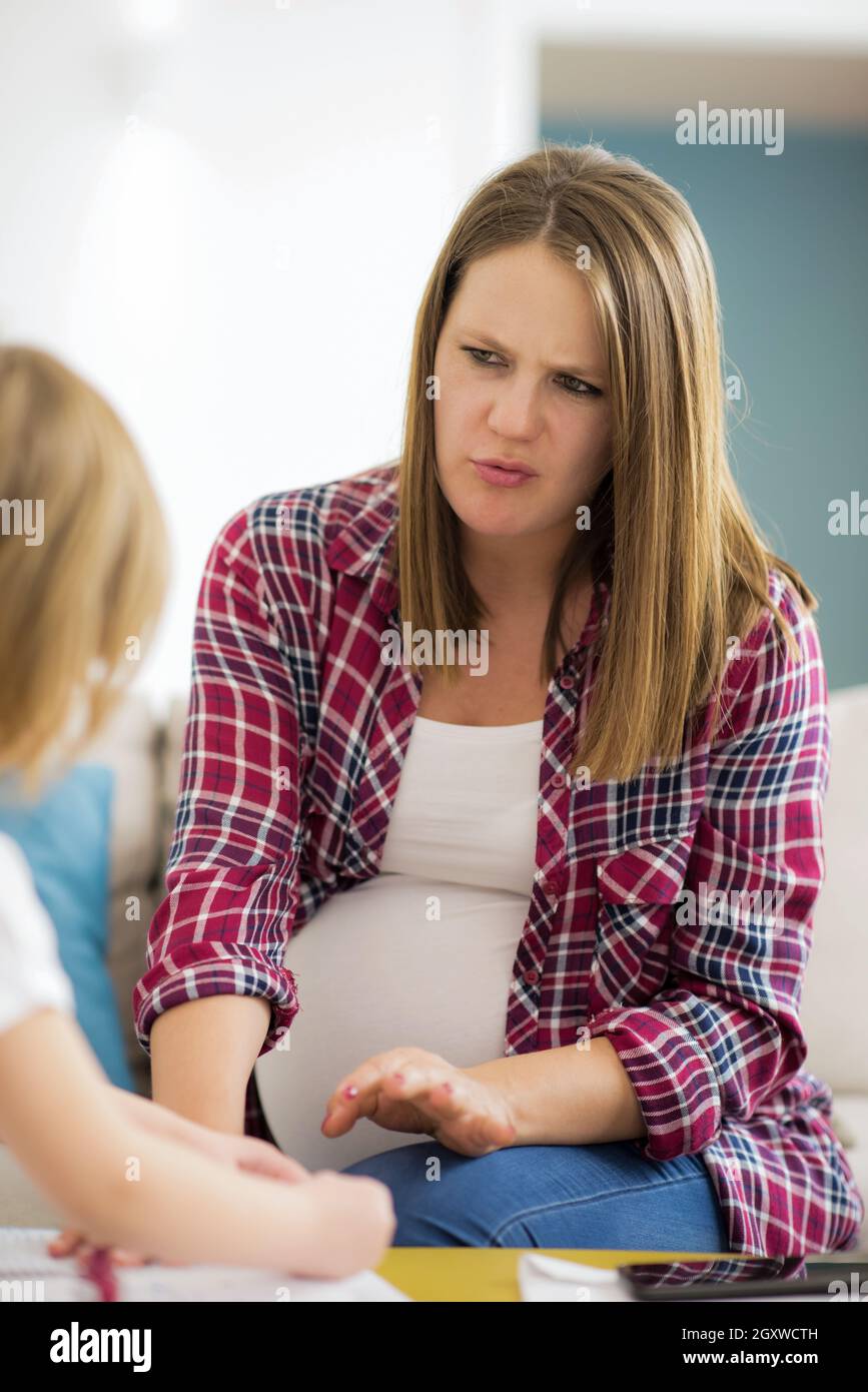 little cute daughter painting nails to her pregnant mom while relaxing